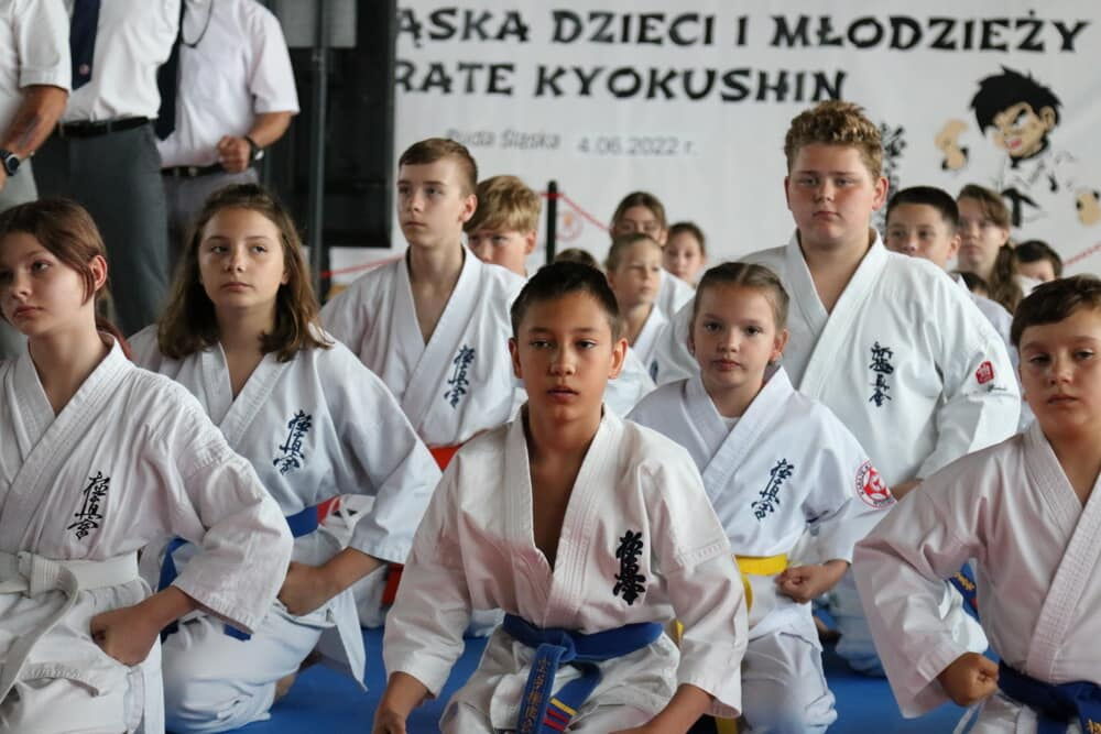 Dzieci ubrane w kimona siedzą na matach.
