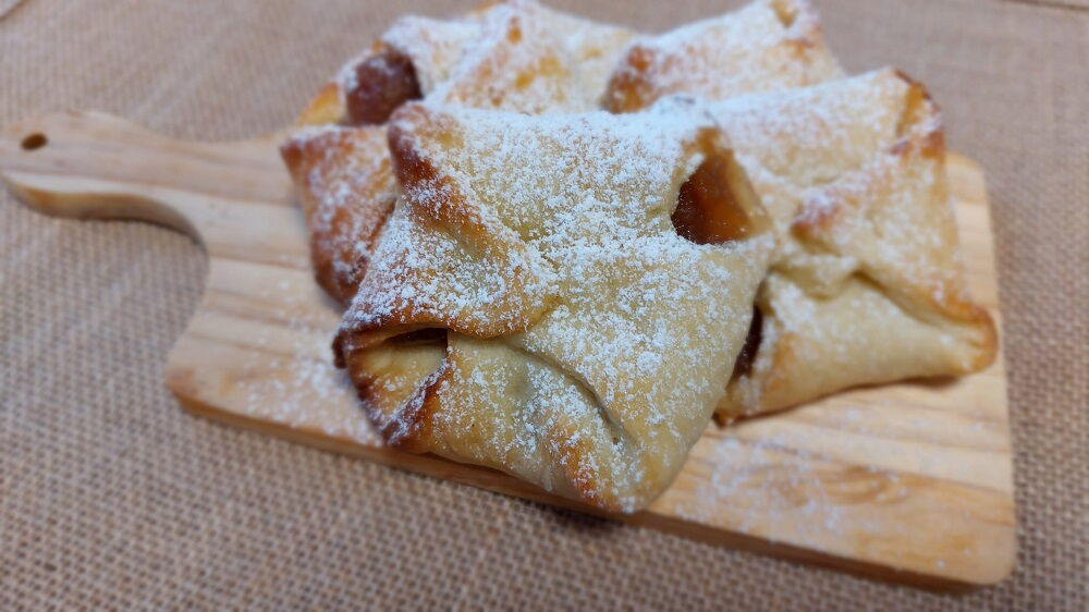 ciasteczka posypane cukrem pudrem, ułożone na drewnianej desce