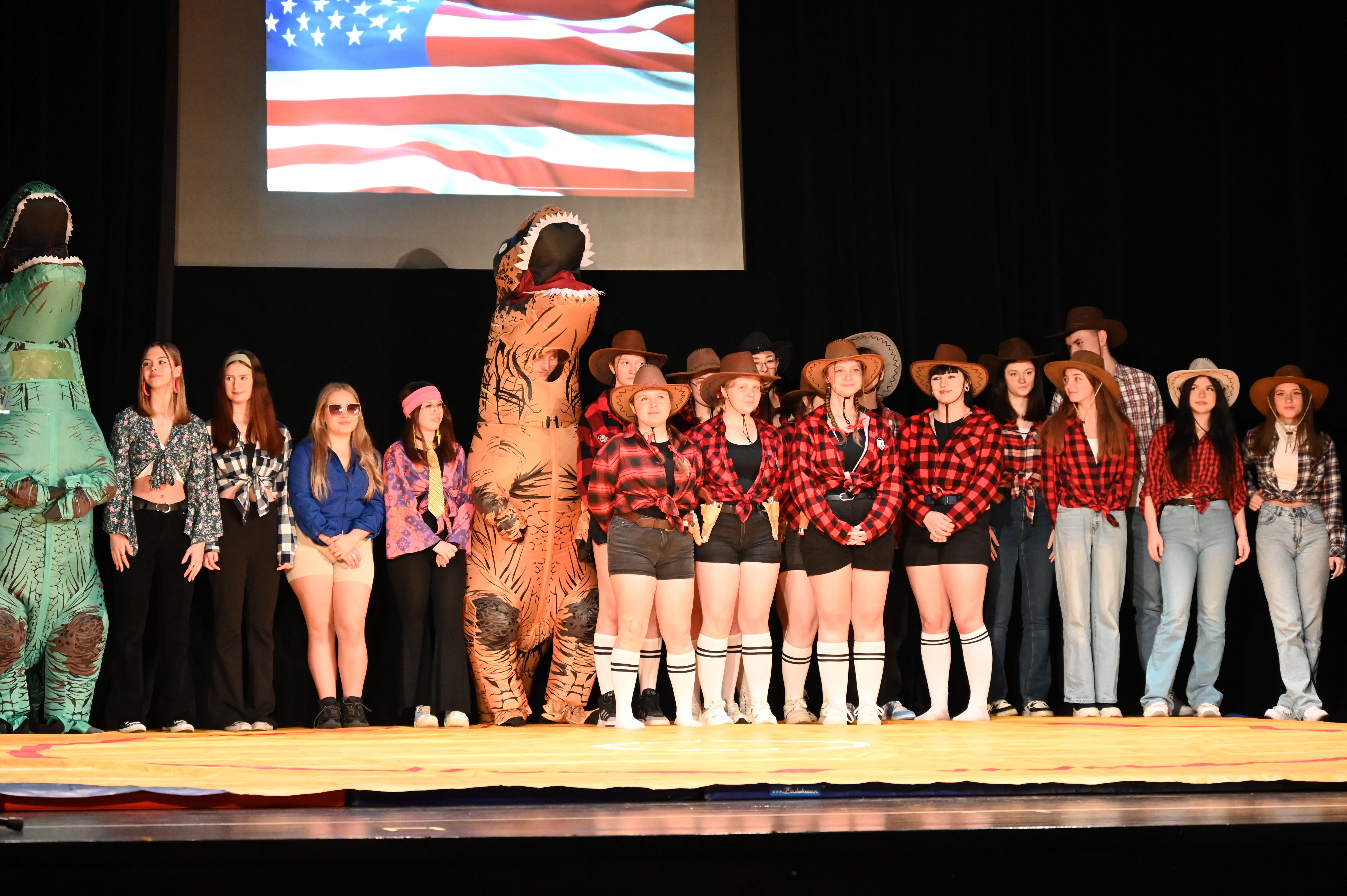 Kilkanaście osób w strojach kowbojów i dinozaurów pozuje do zdjęcia.