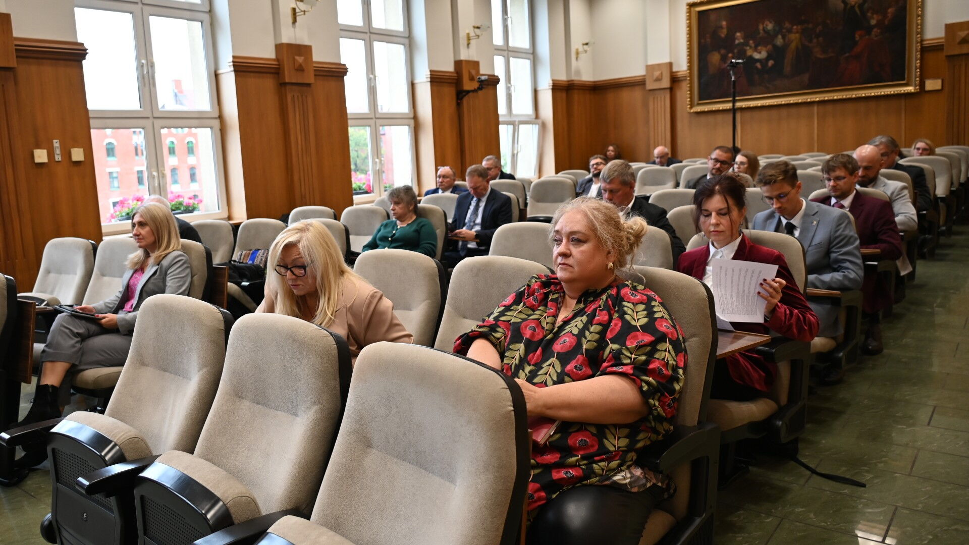 Grupa osób siedzi w fotelach w sali obrad.