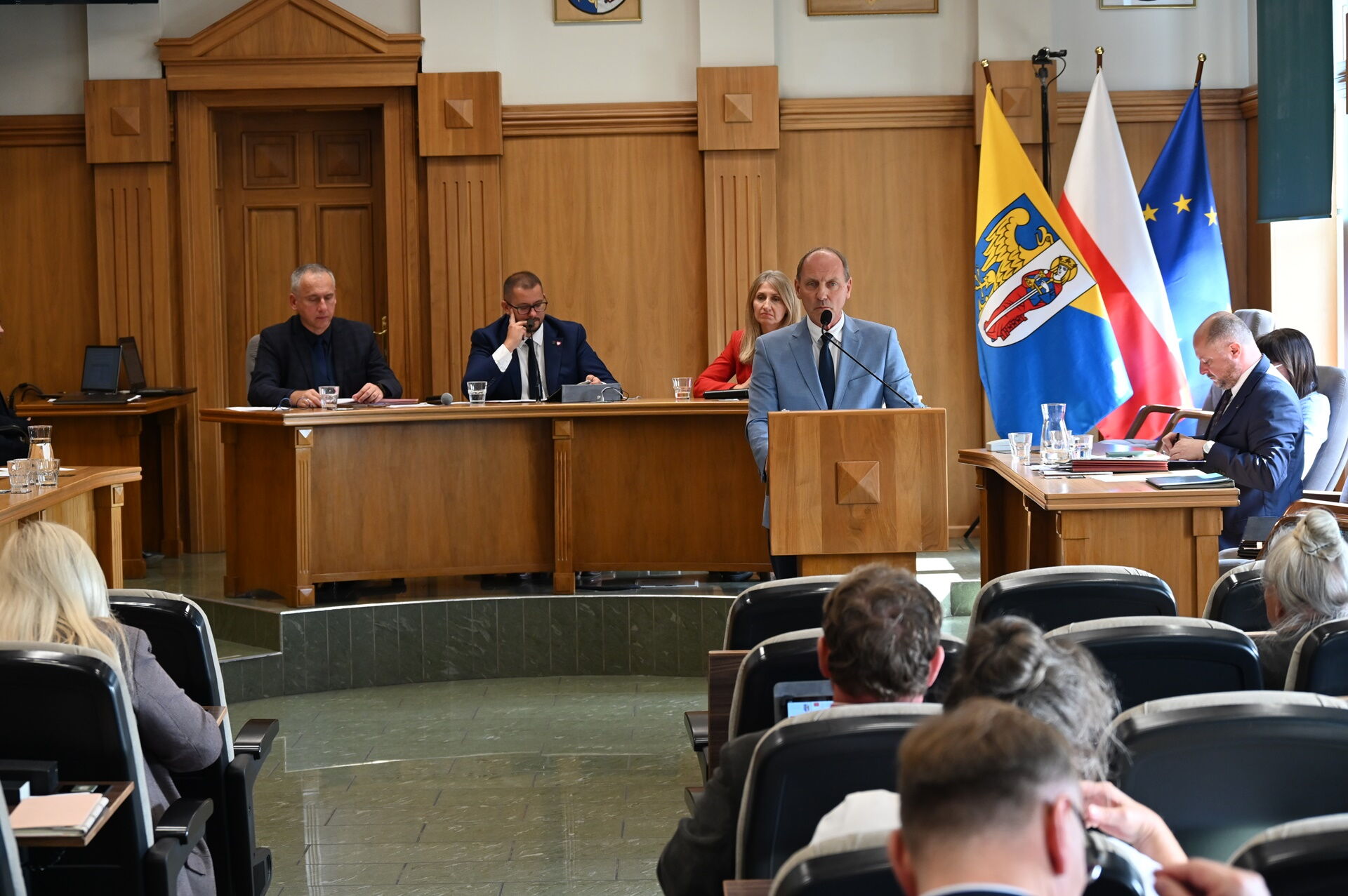 Sala sesyjna - przy mównicy mężczyzna.