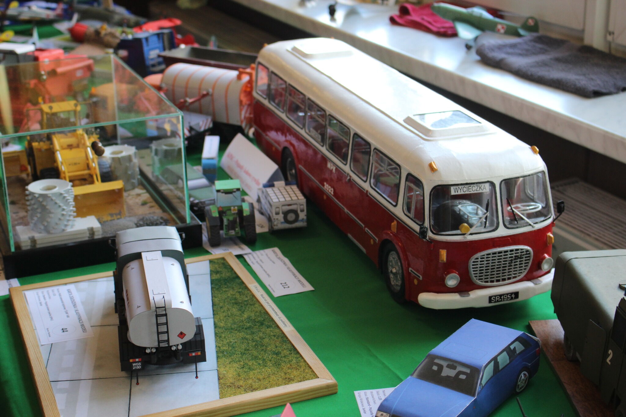 Kilka modeli kartonowych: autobus, samochód, ciężarówki, koparka.