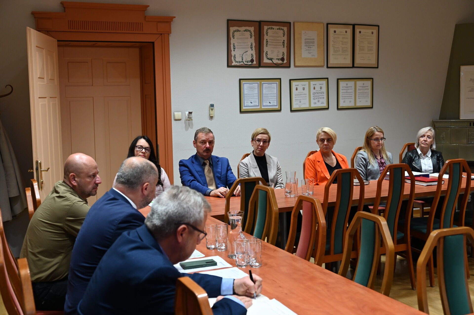 Grupa osób siedzi przy stole w sali konferencyjnej.