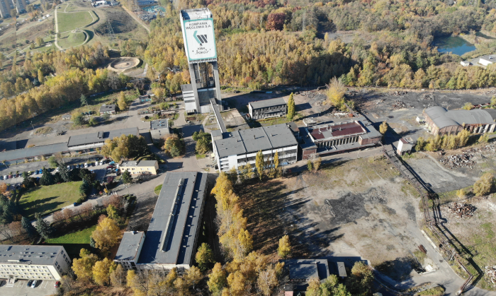 Widok z lotu ptaka na tereny pokopalniane z wieżą szybową z napisem "Kompania Węglowa S.A. KWK Pokój".