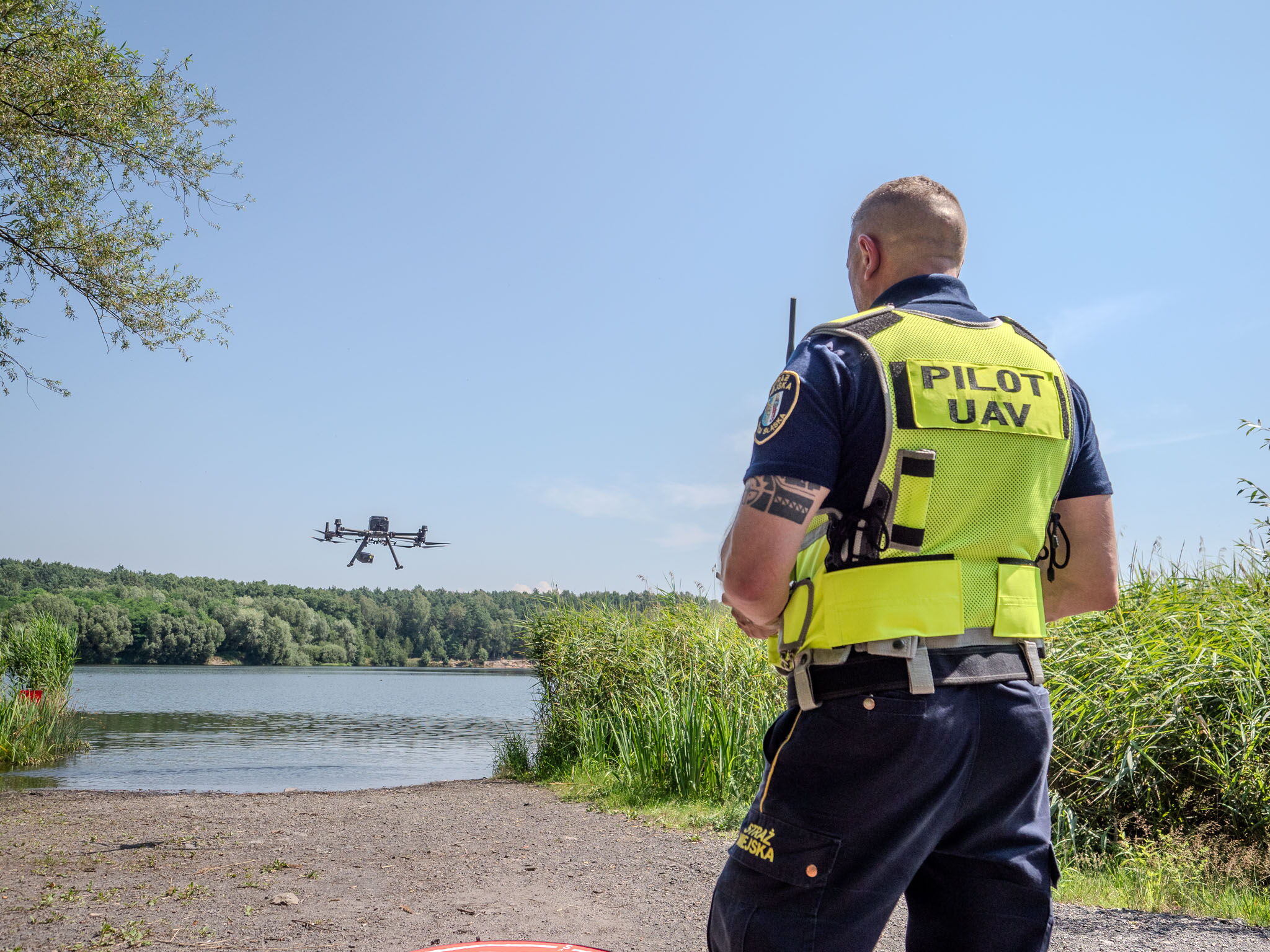 Strażnik miejski z dronem latającym nad stawem.