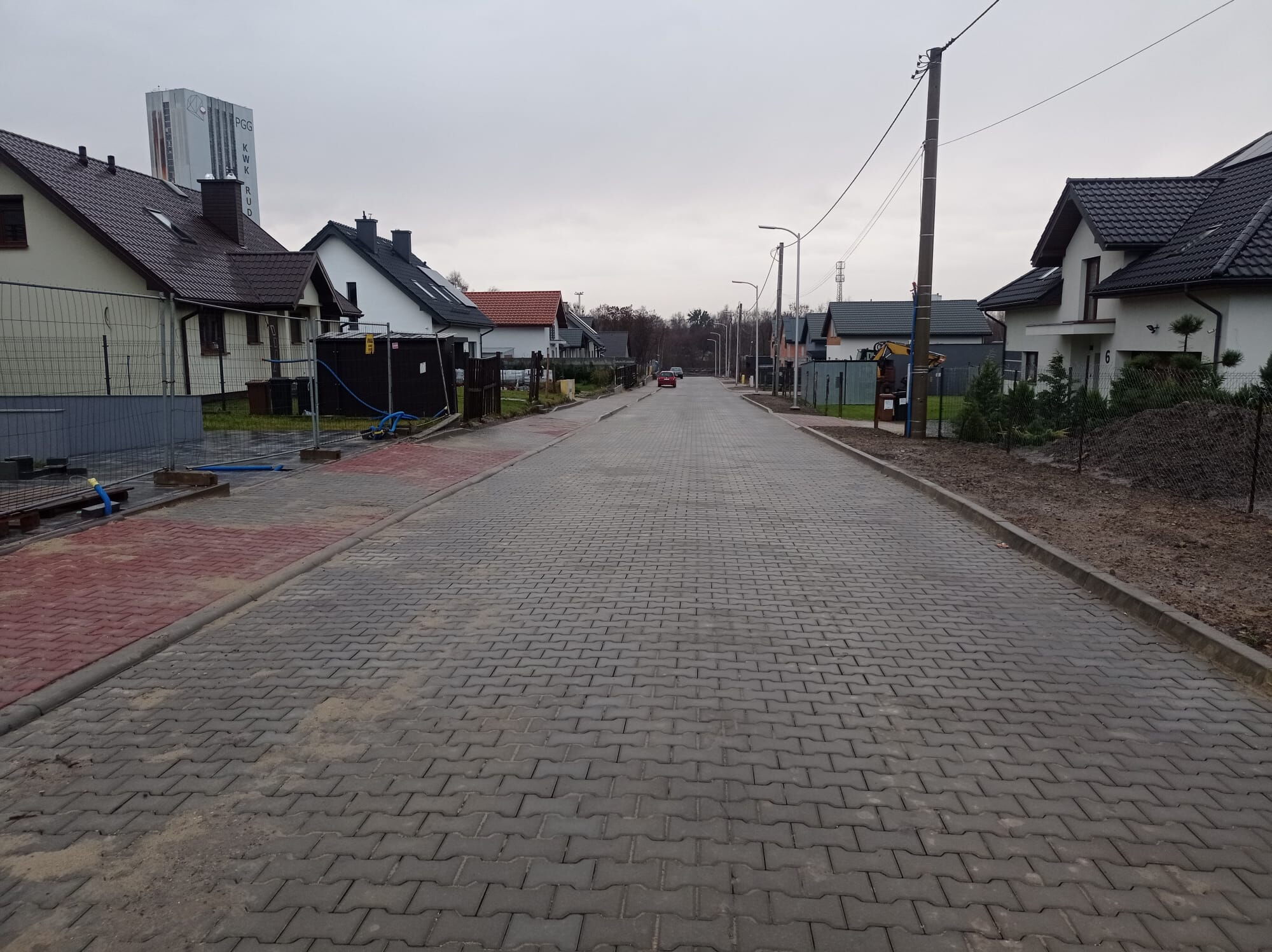 Droga i chodnik z kostki brukowej, po obu stronach domy