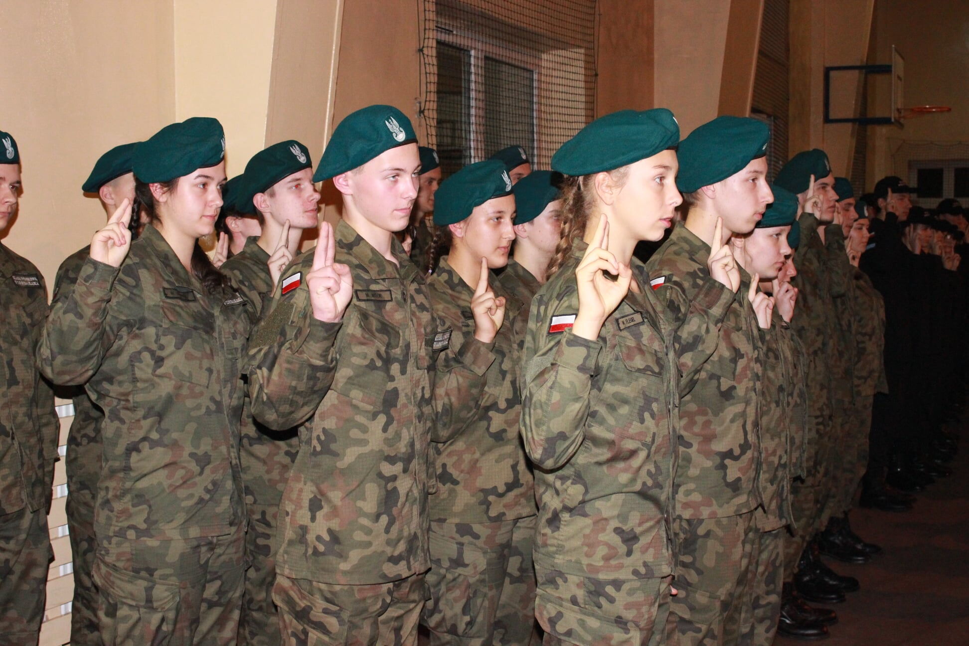 Młodzi ludzie w wojskowych strojach składają ślubowanie.