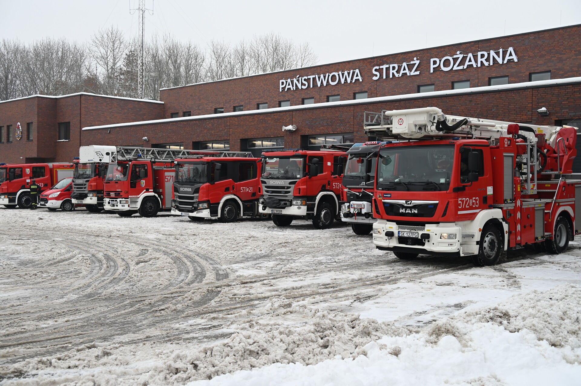 Wozy strażackie przed budynkiem z napisem "Państwowa Straż Pożarna".