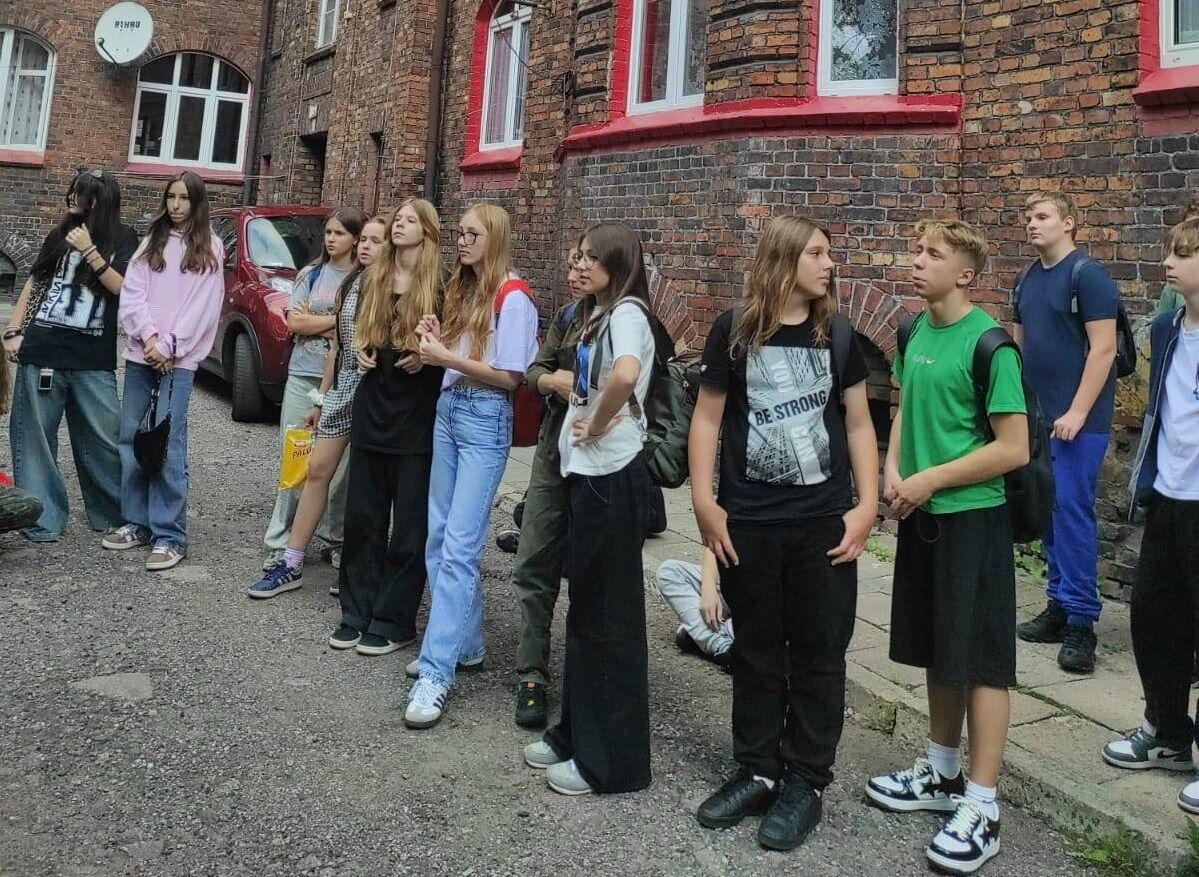 Grupa dzieci stoi pry jednym z budyków na Nikiszowcu
