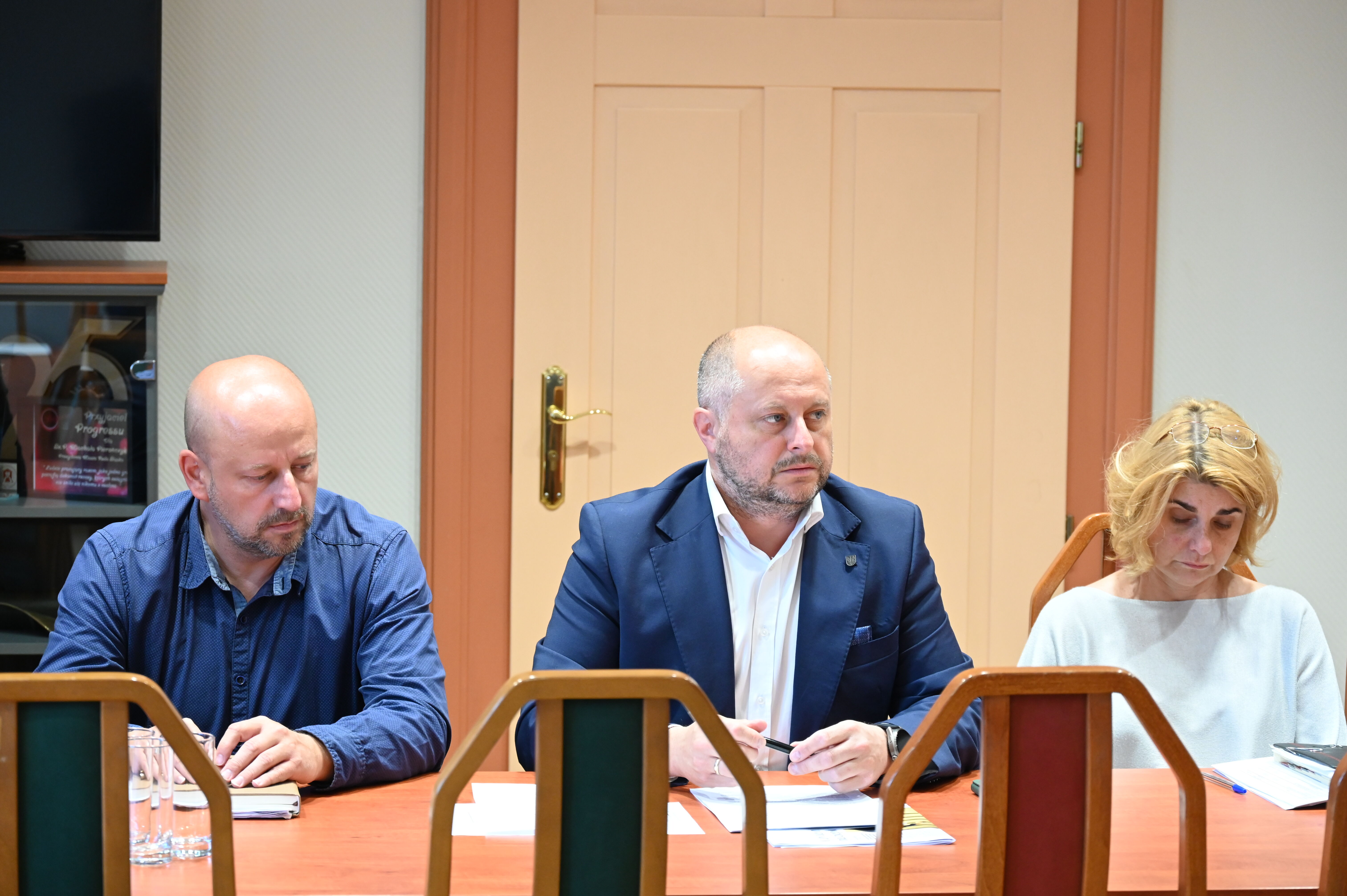 Dwóch mężczyzn i kobieta siedzą przy stole.