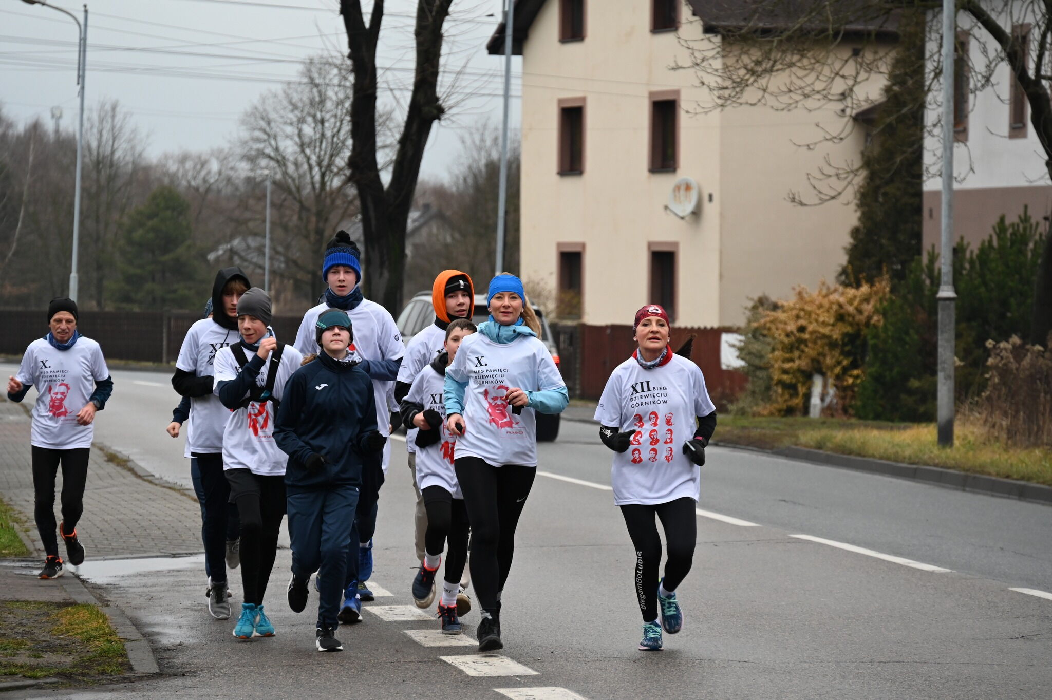 Kilka osób w róznym wieku biegnie po ulicy.