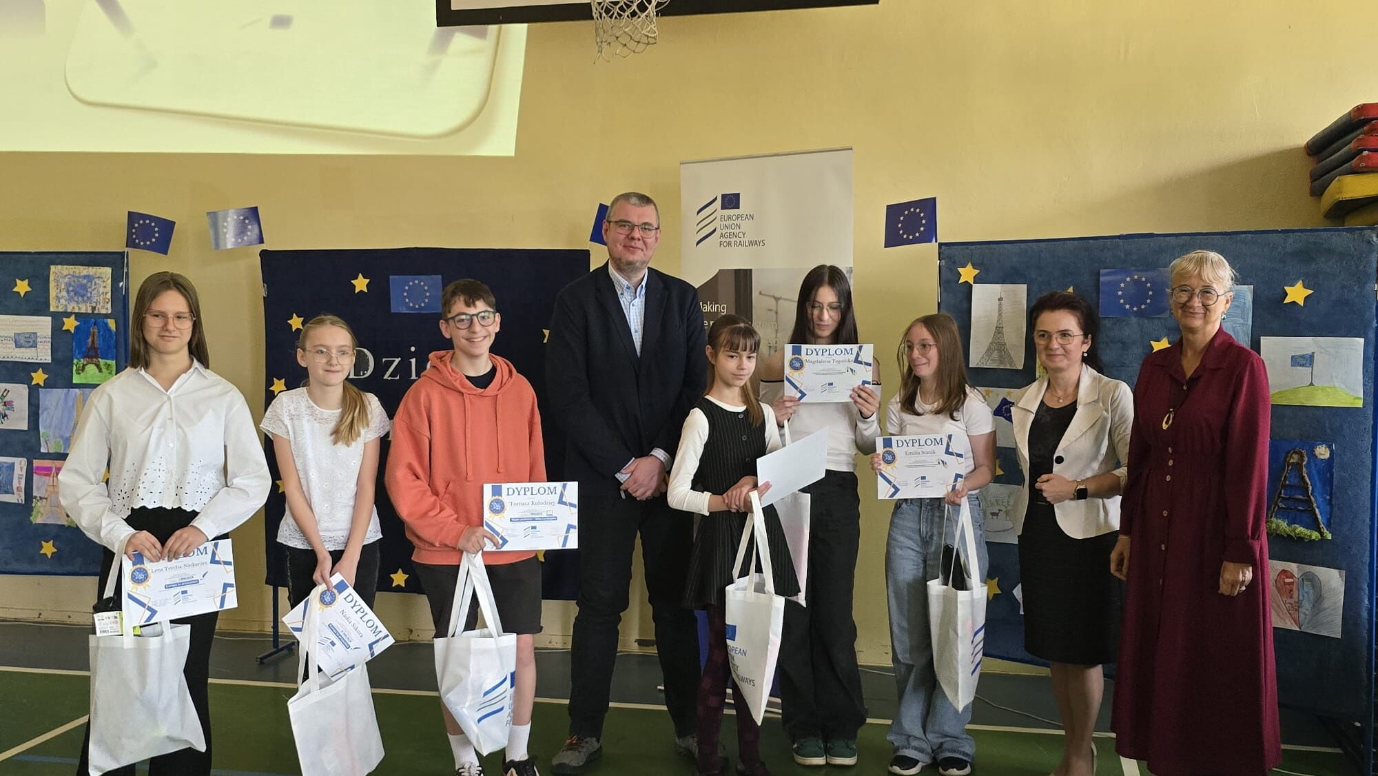 Szkoła - stoi grupa uczniów oraz dwoje dorosłych.