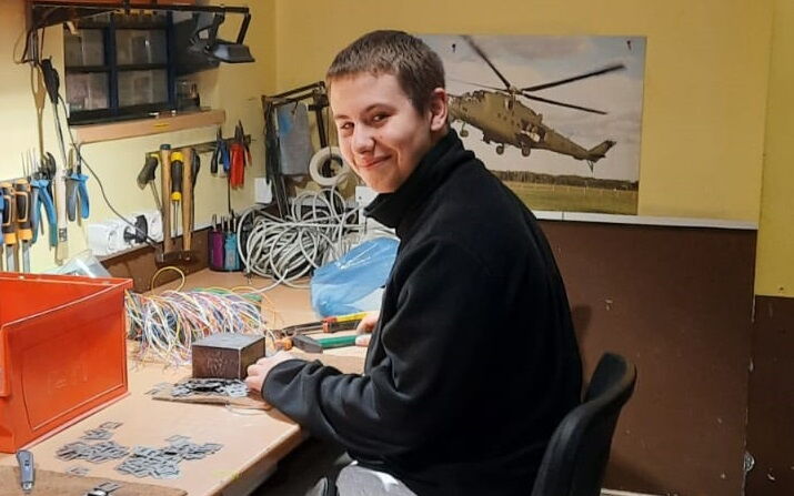 Chłopak siedzący przy stole z róznymi narzędziami.