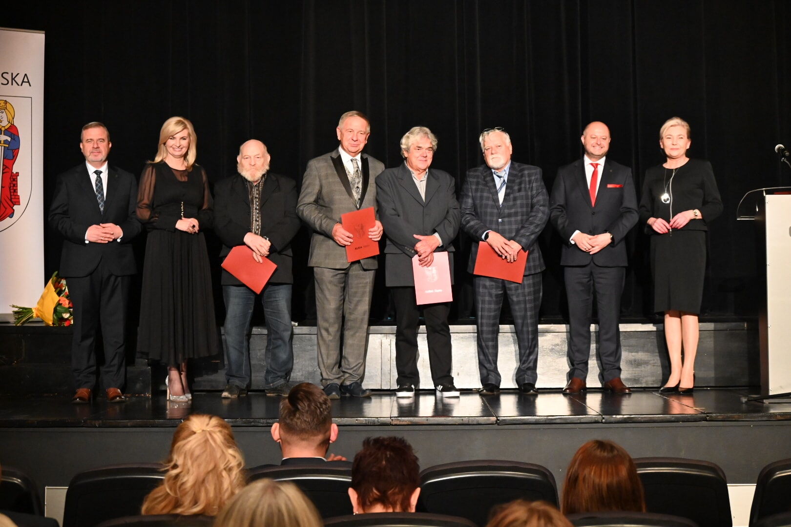 Osiem osób stoi na scenie.