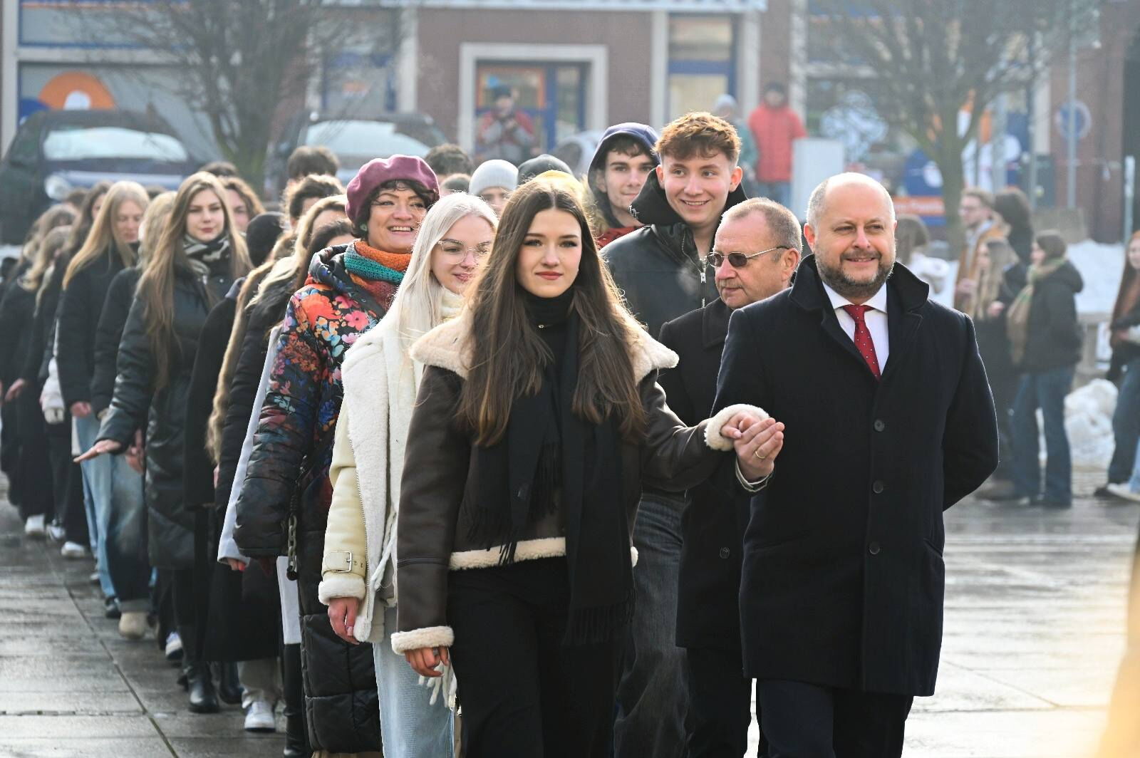 w plenerze, osoby idą w parach jedna za drugą, tańcząc poloneza