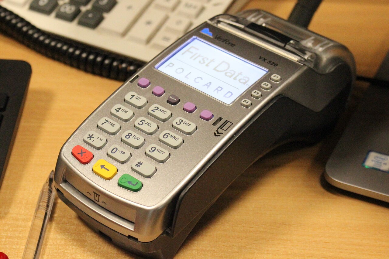 Terminal płatniczy, fragment klawiatury komputerowej, długopis.