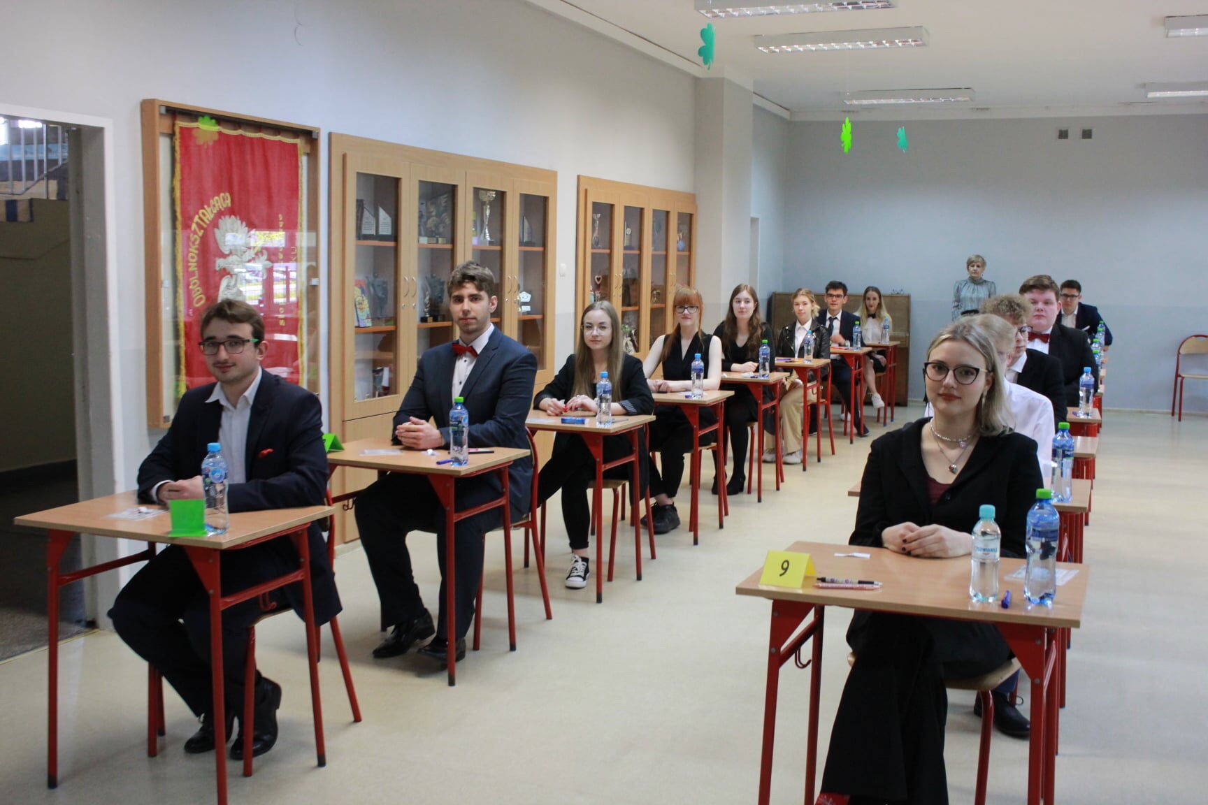 Młodzi ludzie siedza przy stolikach.