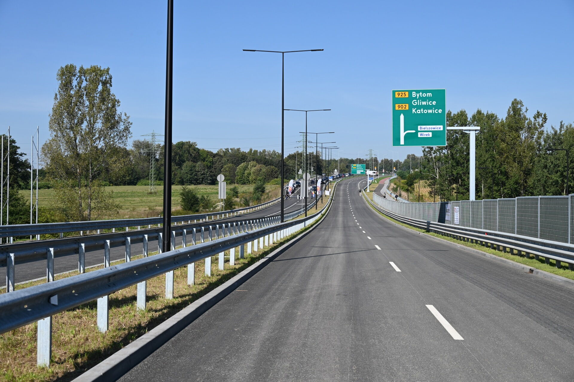 Droga, latarnie uliczne, drogowskazy, drzewa.