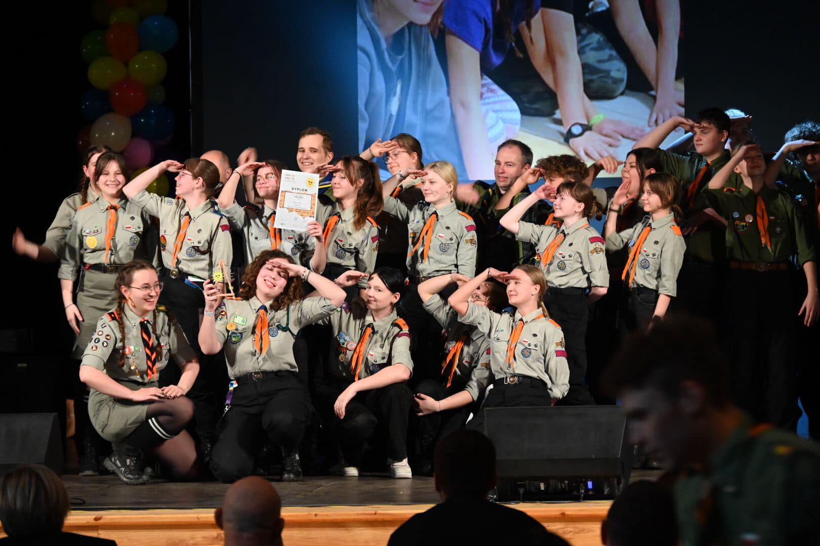 Grupa harcerzy stoi na scenie.