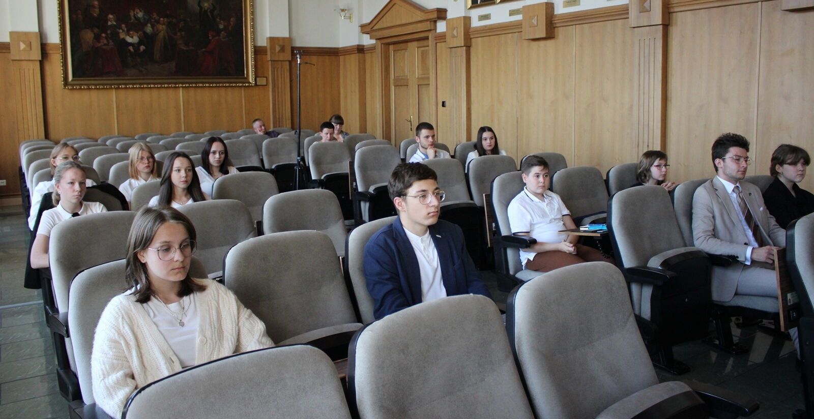 Grupa młodzieży siedząca na fotelach wewnątrz pomieszczenia