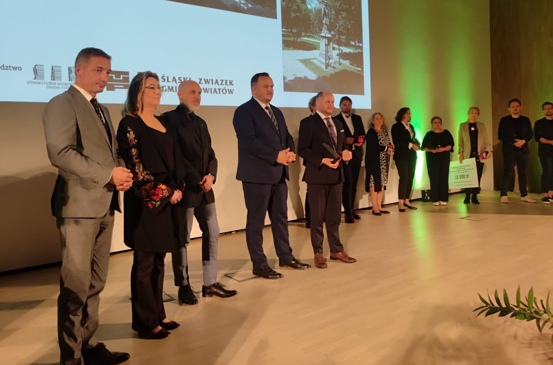 Grupa osób na scenie, w tle plansza ze zdjęciami i napisem "Śląski Związek Gmin i Powiatów".