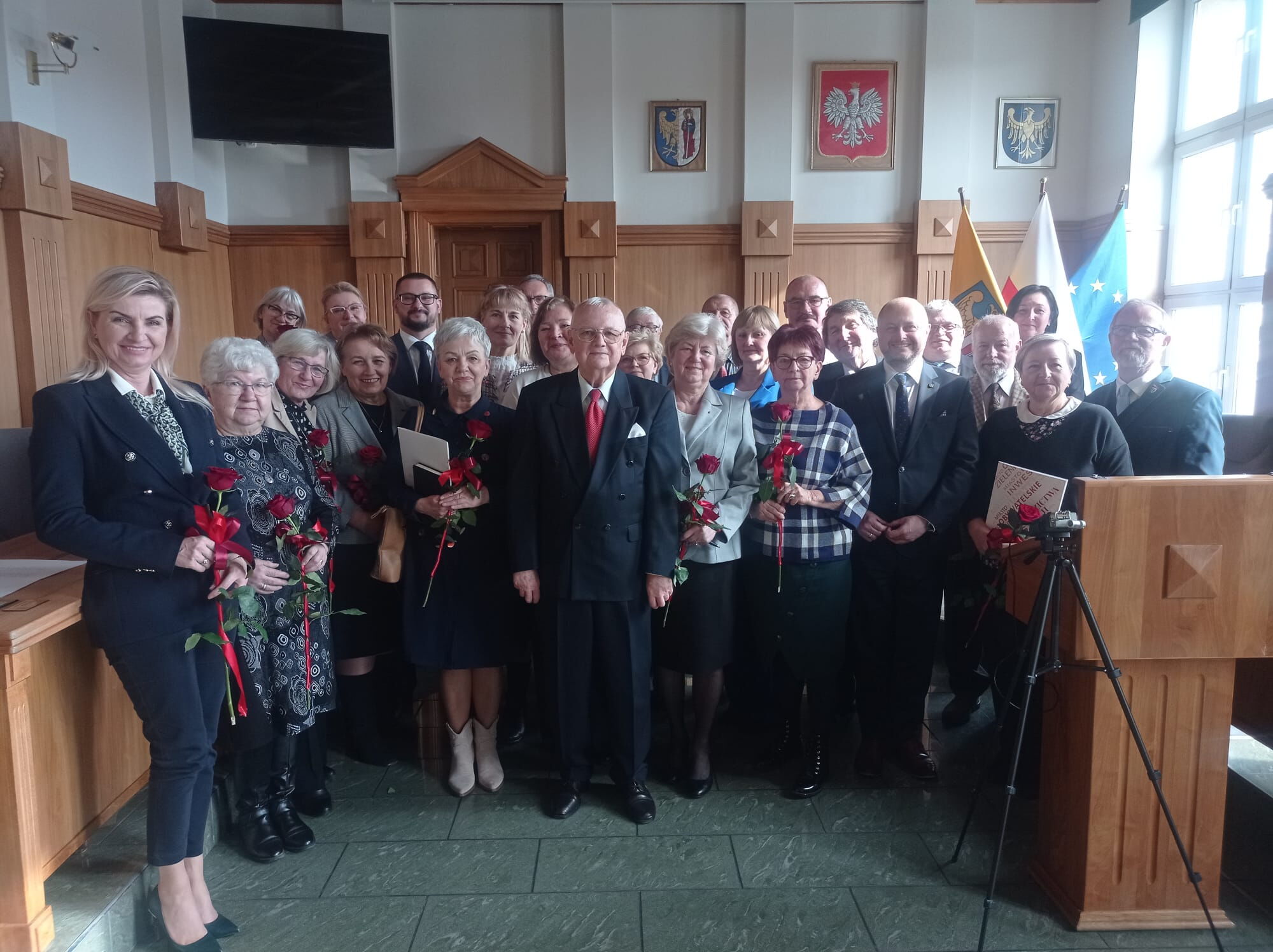 Grupa seniorów pozuje do zdjęcia razem z władzami miasta