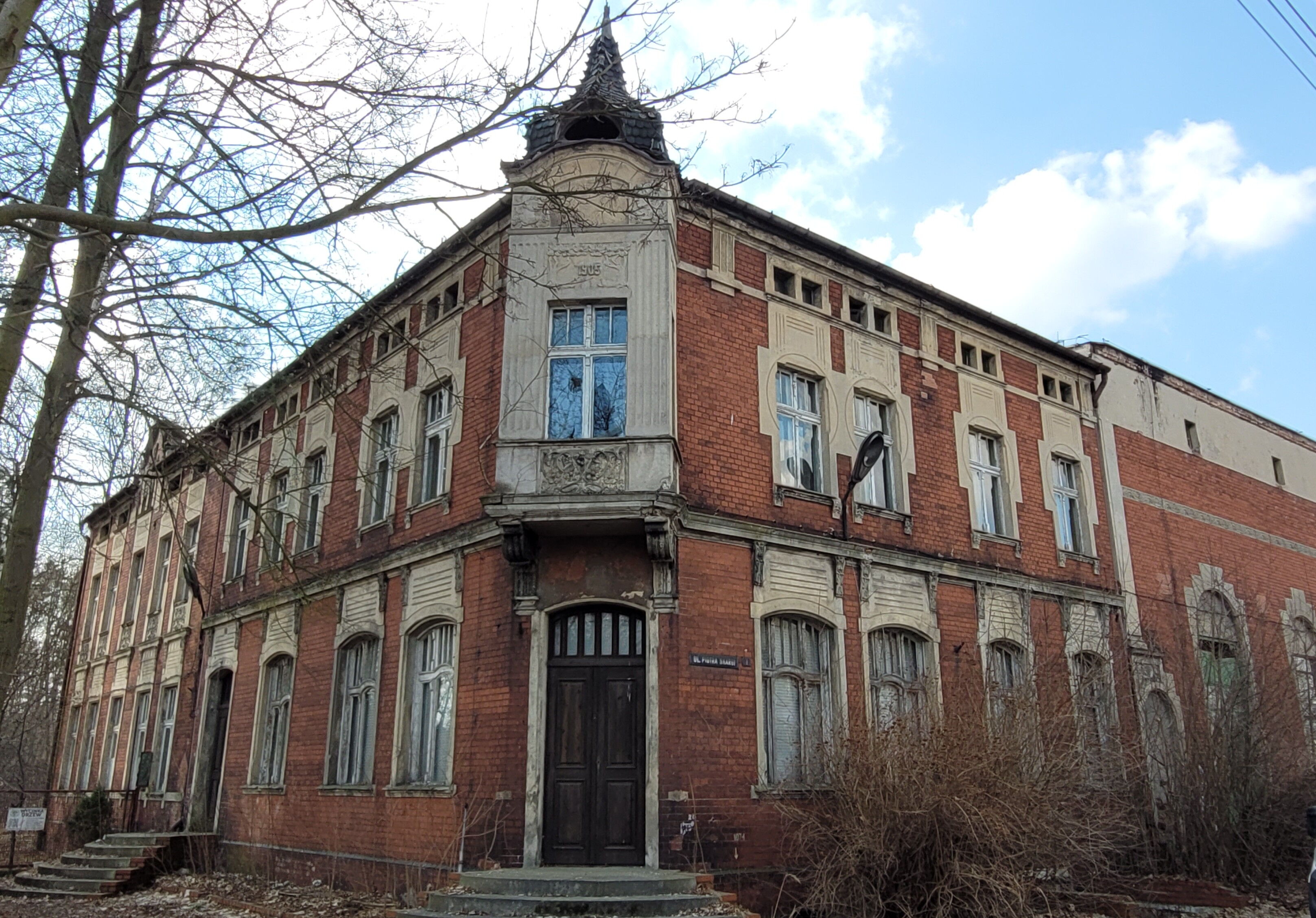 Piękny, zabytkowy budynek z czerwonej cegły, ale zaniedbany.