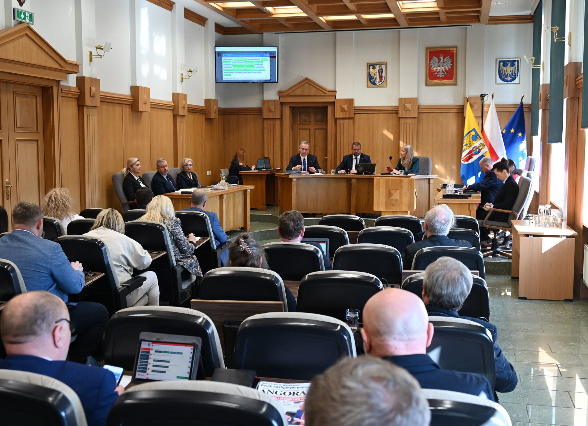 Wnętrze sali sesyjnej - grupa radnych siedzi w fotelach.