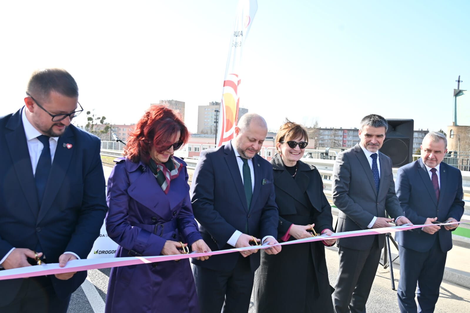 Grupa ludzi przecina wstegę.