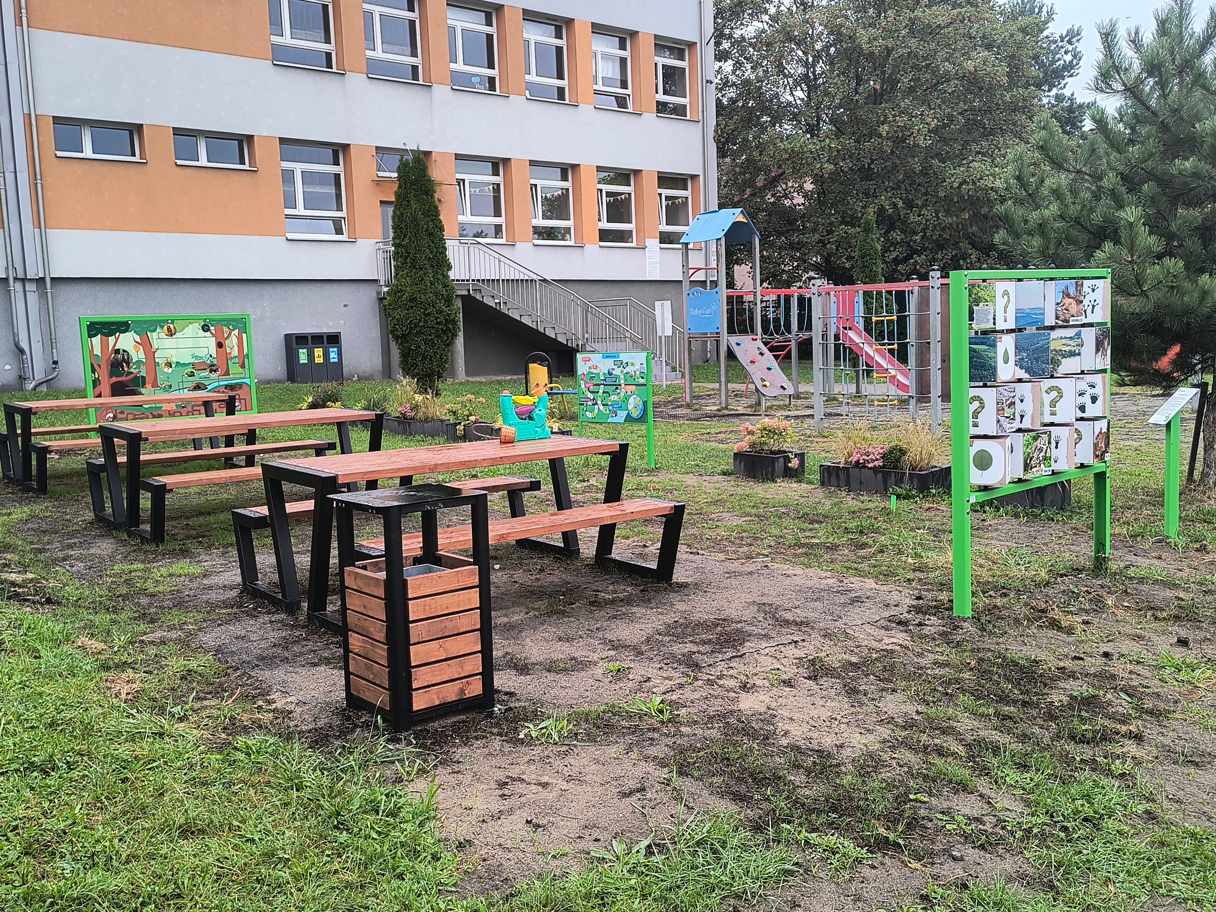 Widok na ławki i stoły oraz budynek szkoły.