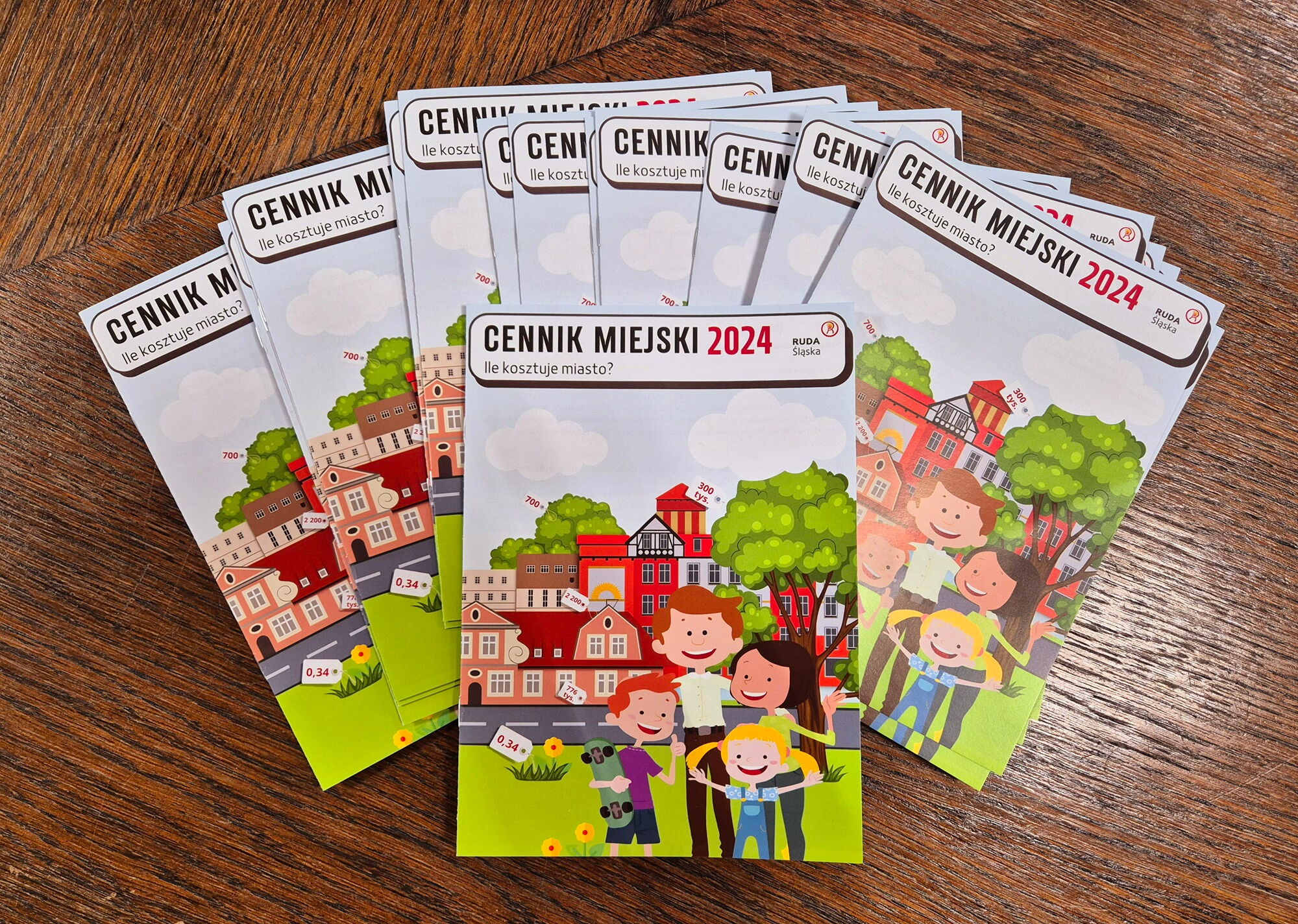Kilka broszur cennik miejski leży na ciemnym drewnianym stole.
