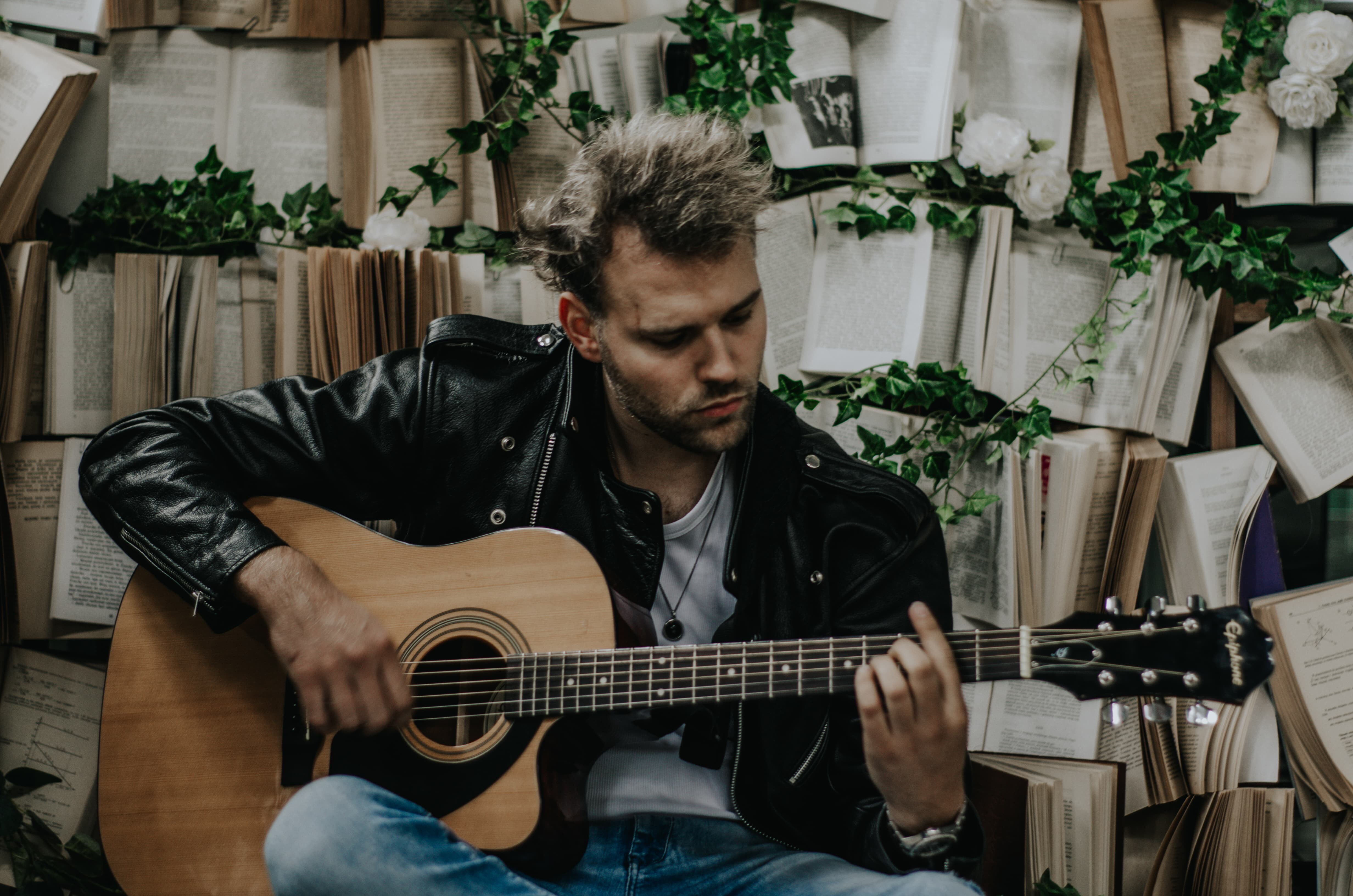 Młody mężczyzna gra na gitarze.