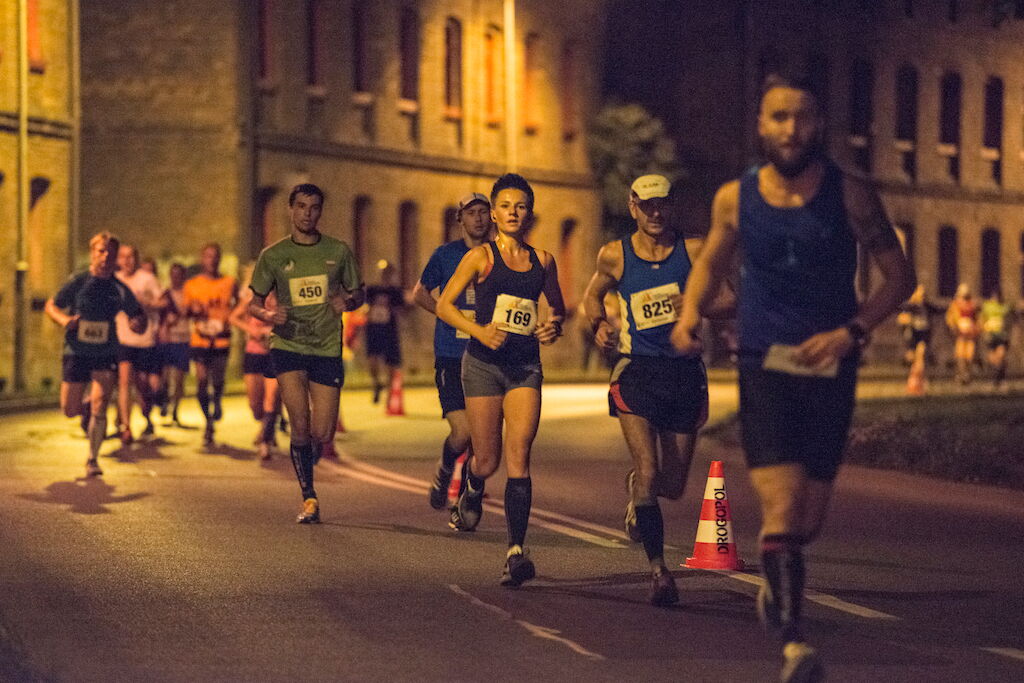 Kilkoro biegaczy biegnie po jezdni.