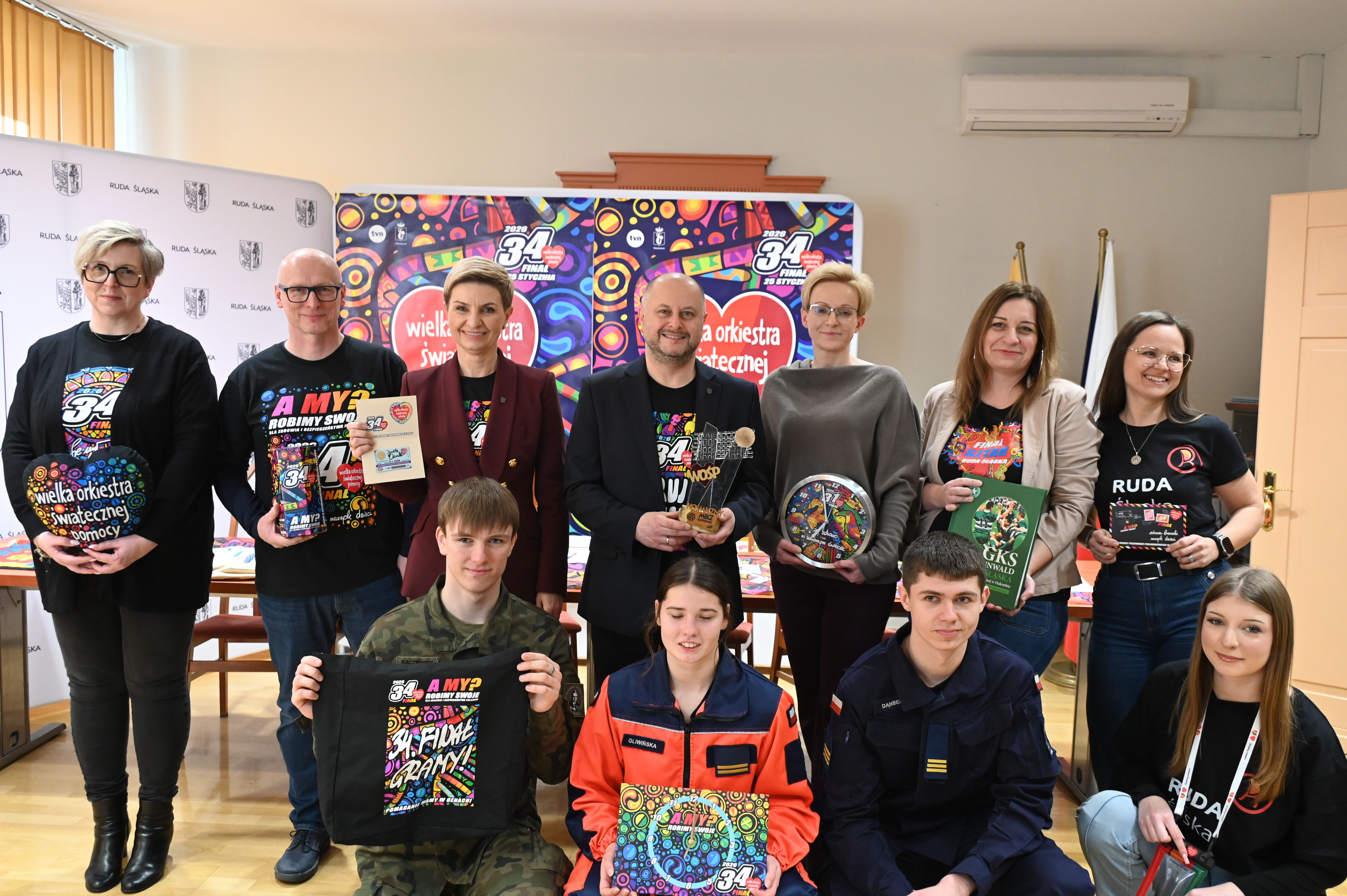 grupa osób pozuje do zdjęcia z gadżetami