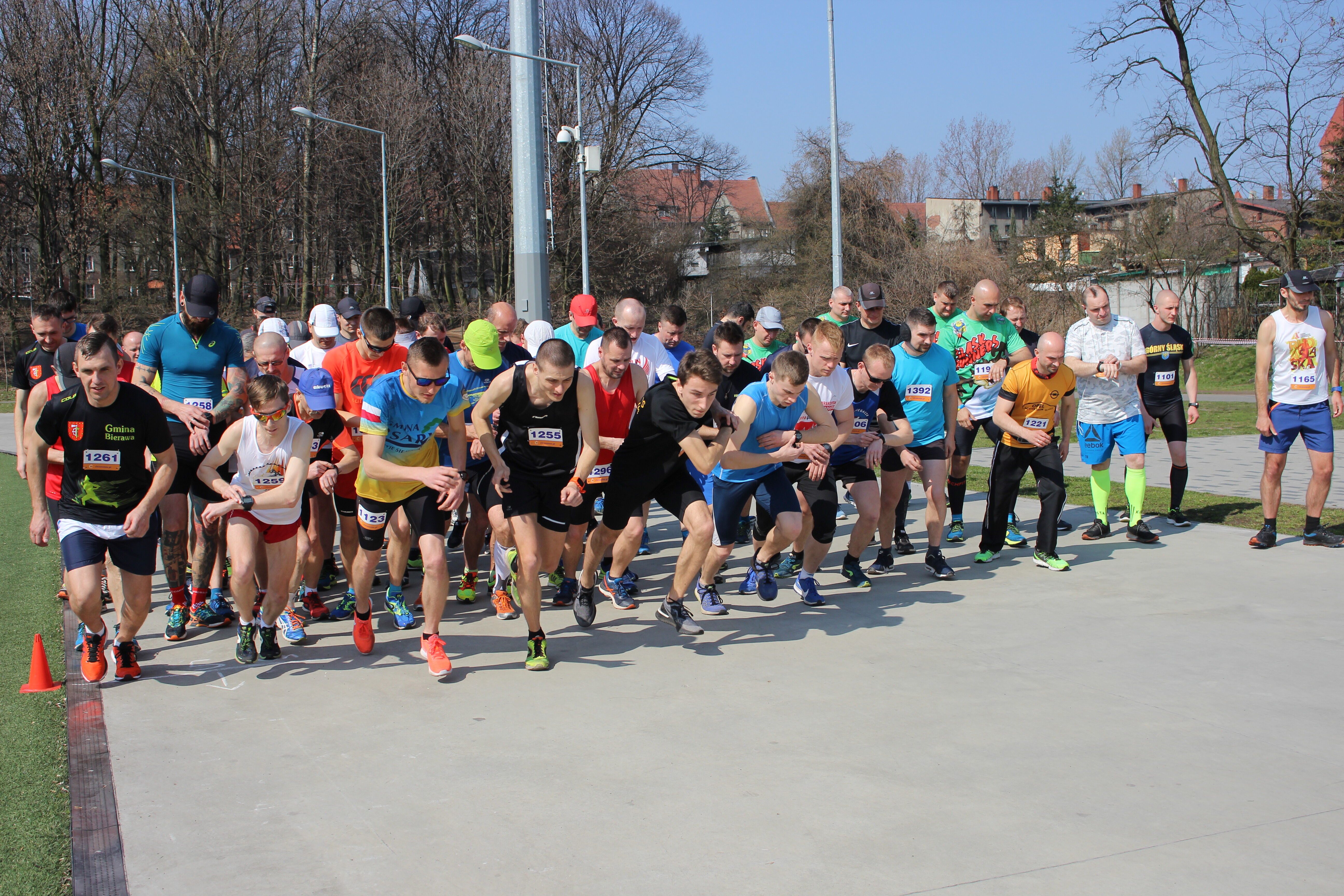 Grupa biegaczy biegnie po bieżni.