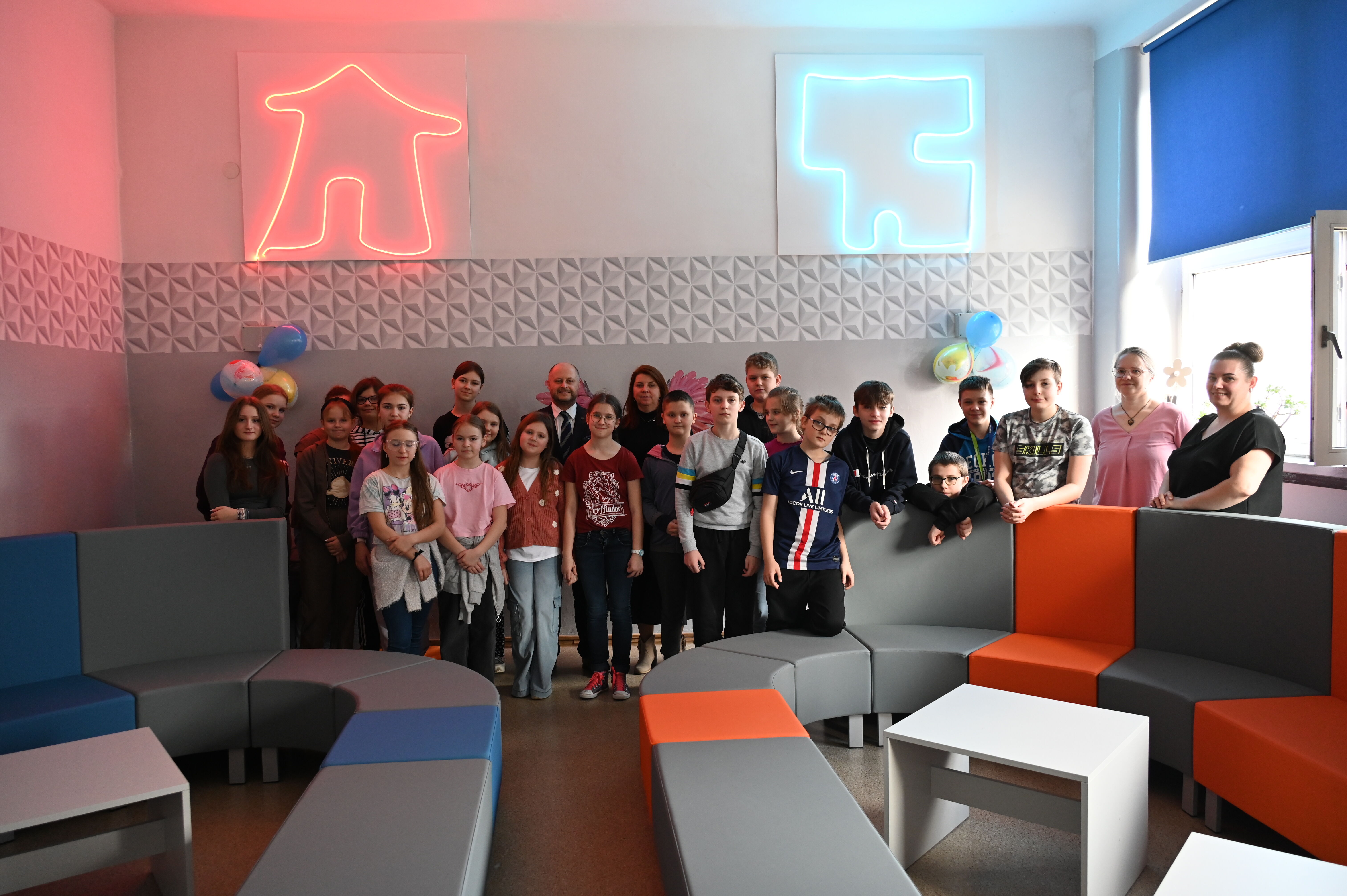 Dzieci i dorosli pozują do zdjęcia w sali chillout.