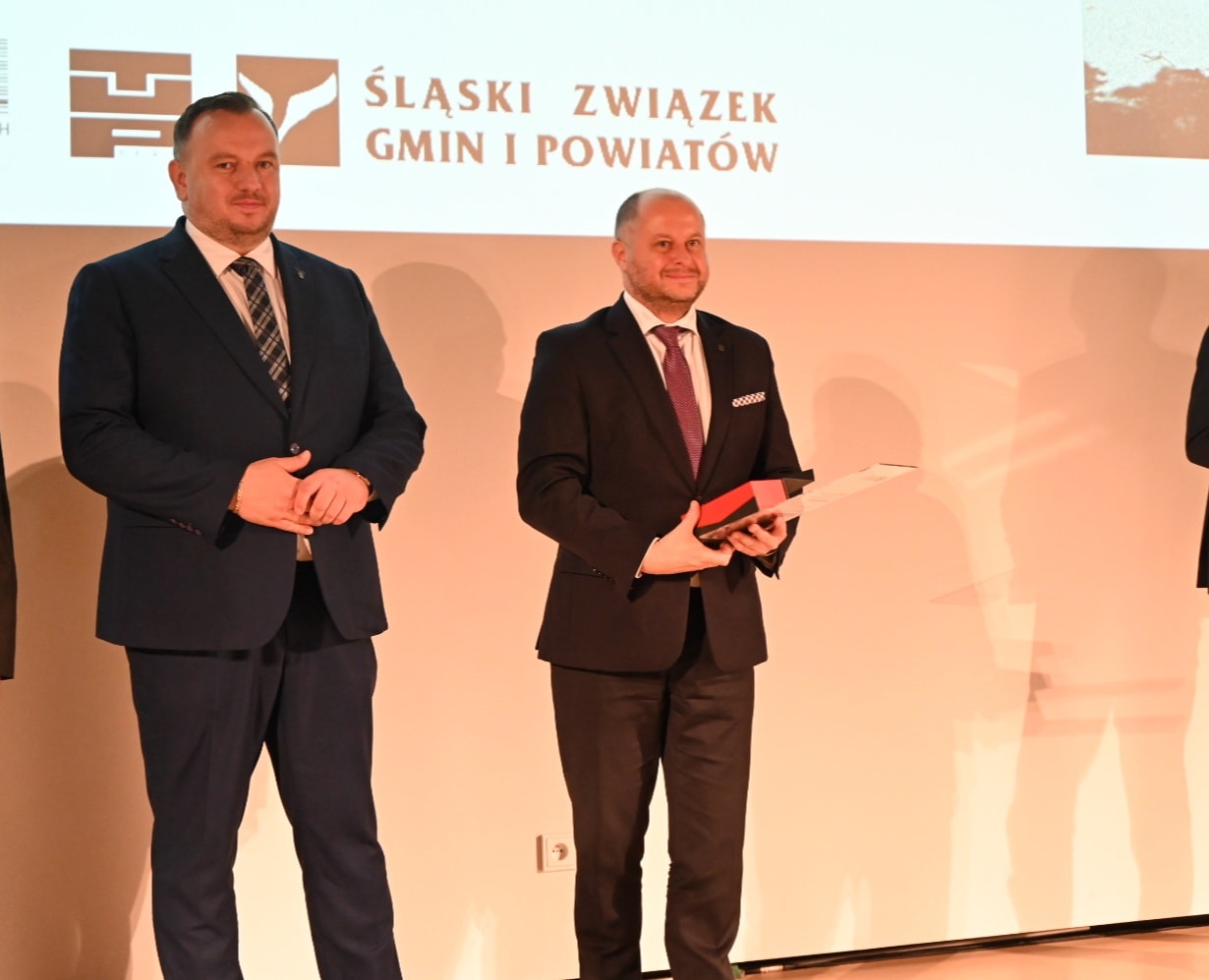 Dwóch mężczyzna w garniturach, tle plansza z tekstem "Śląski Związek Gmin i Powiatów".