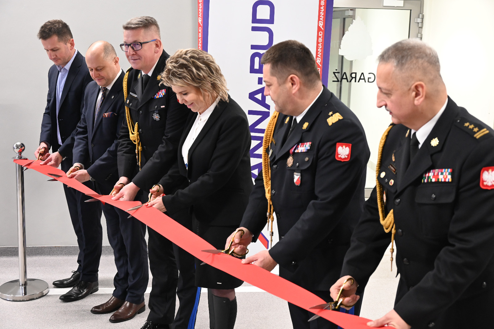 Sześć osób przecina wstęgę, trzy z nich w mundurach strażackich.