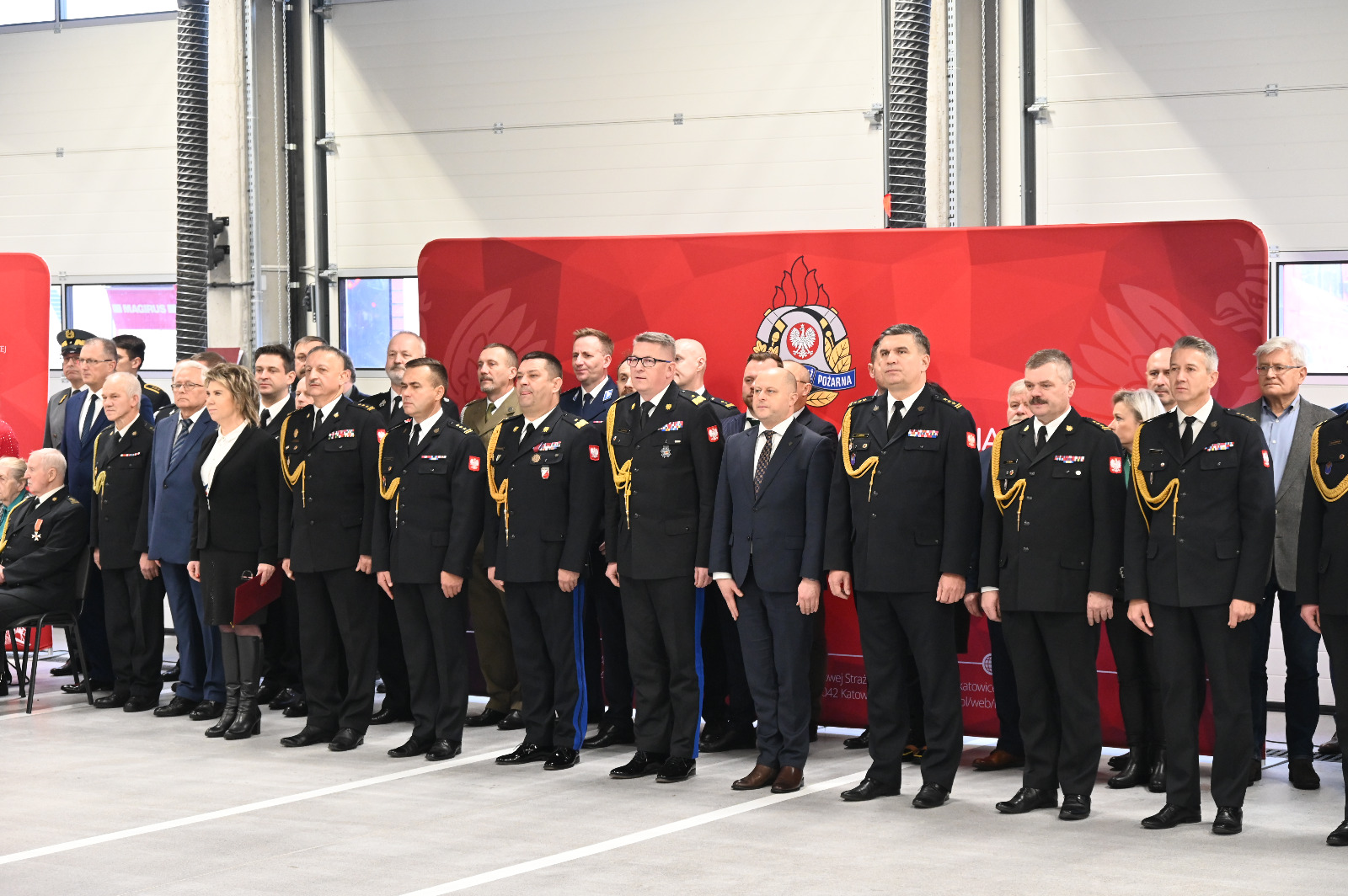 Grupa osób, część w mundurach strażackich.