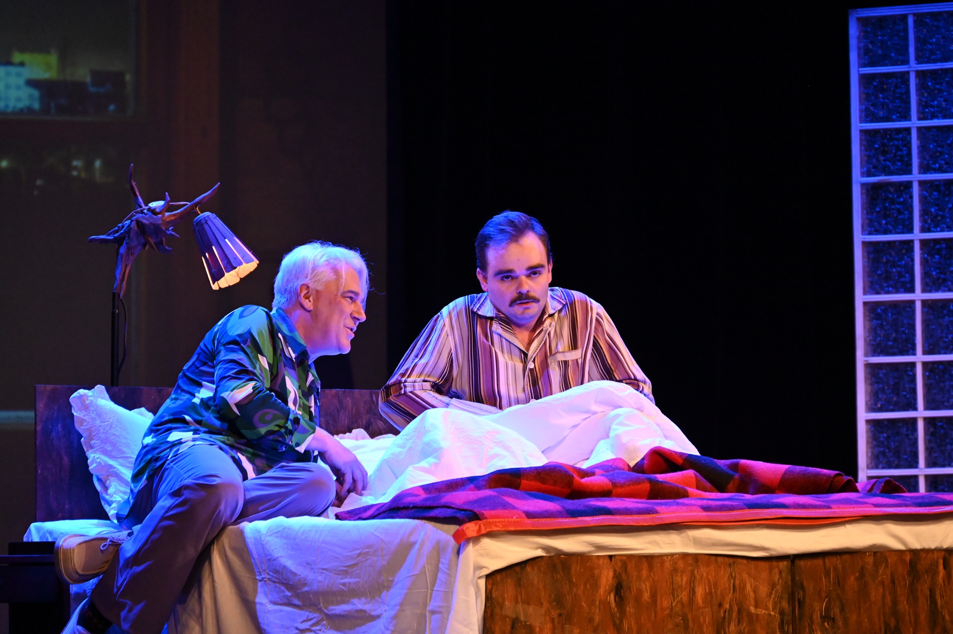 Scena w teatrze - dwaj mężczyźni leżą na łóżku.